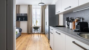 Cozinha moderna com armários brancos, uma mesa de jantar com cadeiras e vista para a sala de estar.