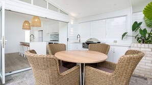 Eine moderne Küche mit weißen Schränken, einem runden Holztisch und Korbstühlen.