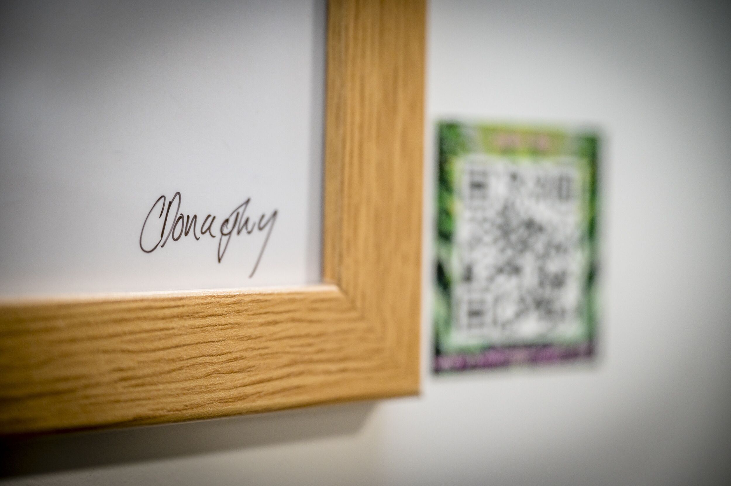 A framed artwork with the name "Clonaghy" and a QR code on the wall.