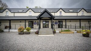 A building with a symmetrical facade, a central entrance with steps, and a gravel courtyard.