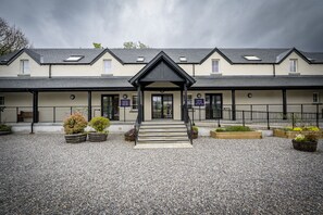 A building with a symmetrical facade, a central entrance with steps, and a gravel courtyard.