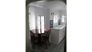A kitchen with a dining table and chairs, a white countertop, and a window.