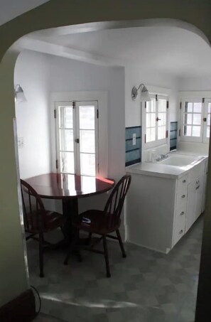 Une cuisine avec une table et des chaises, un plan de travail blanc et une fenêtre.