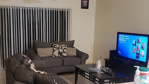Un salon comprenant un canapé, une table basse, un téléviseur et un ventilateur de plafond.