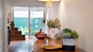Un pasillo con suelo de madera, una mesa con lámpara, un florero y una planta en maceta.