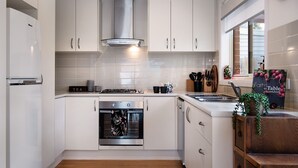 Una cocina moderna con armarios blancos, electrodomésticos de acero inoxidable y una ventana con vistas al exterior.