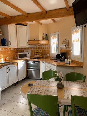 A kitchen with white cabinets, a microwave, a coffee maker, and a table with chairs.