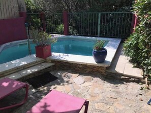 Un jardin avec une piscine, des marches en pierre et des plantes en pot.