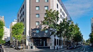 A modern hotel with a prominent 'TRIBE' sign, multiple floors, and a parking area. - Tribe Paris La Defense Esplanade (Courbevoie)