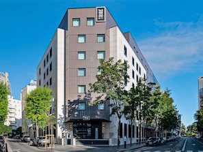 A modern hotel with a prominent 'TRIBE' sign, multiple floors, and a parking area. - Tribe Paris La Defense Esplanade (Courbevoie)
