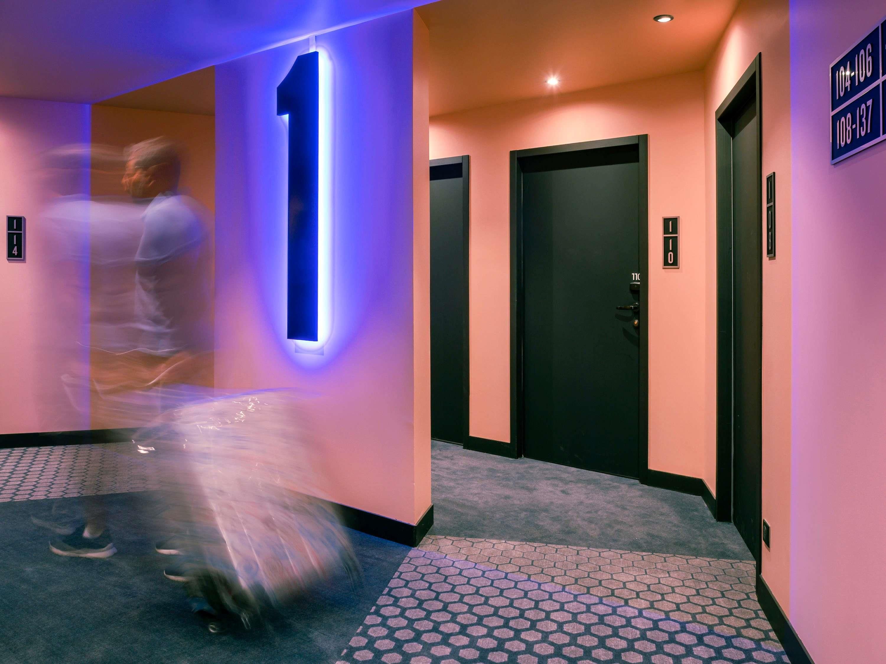A hallway with a number 1 illuminated sign, black doors, and a tiled floor.