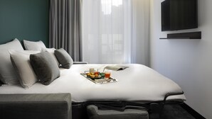 A hotel room with a bed, a TV, a window with curtains, and a tray with breakfast items. - Tribe Paris La Defense Esplanade (Courbevoie)