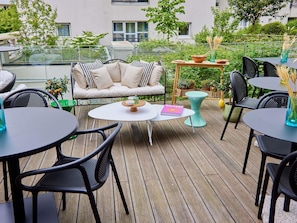 Une terrasse dotée d’un espace salon extérieur, comprenant un canapé, ainsi que plusieurs tables et chaises.