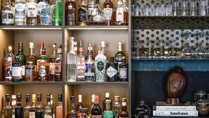 A liquor store with shelves of various alcohol bottles and a display of crystal glasses. - Tribe Paris La Defense Esplanade (Courbevoie)