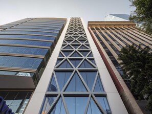 Un immeuble moderne de grande hauteur, doté d’une façade géométrique remarquable, de grandes fenêtres et d’une tour centrale imposante.