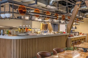 Un espace bar moderne doté d’un comptoir en bois, de sièges et de divers distributeurs de nourriture et de boissons.