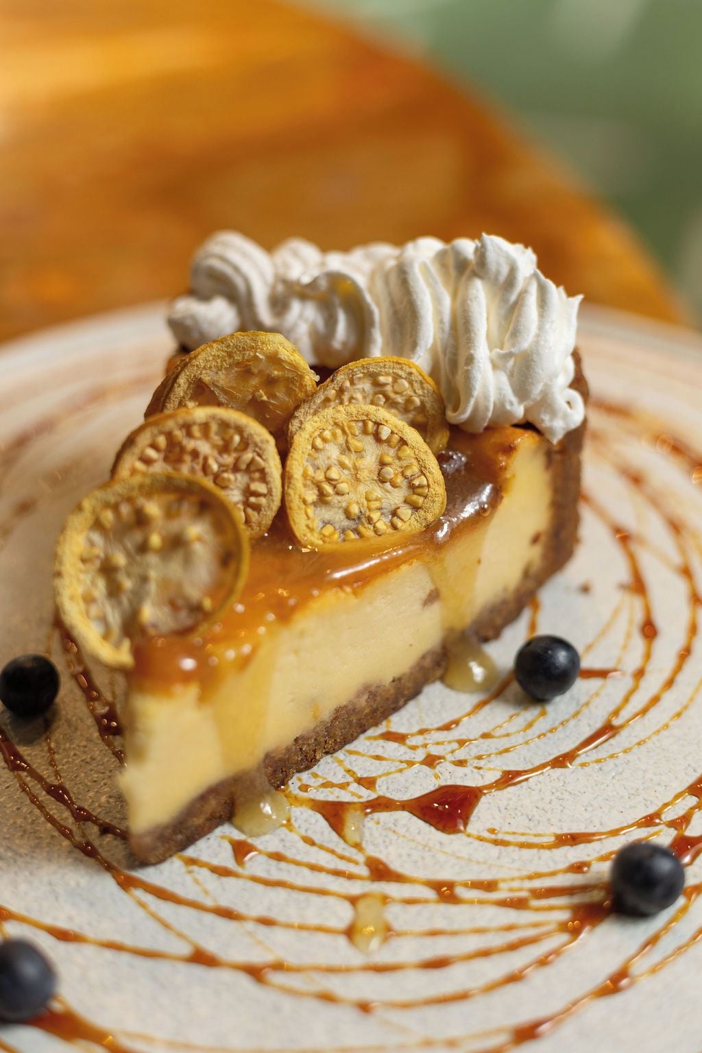 A slice of cheesecake with caramel sauce and a dollop of whipped cream on a plate.