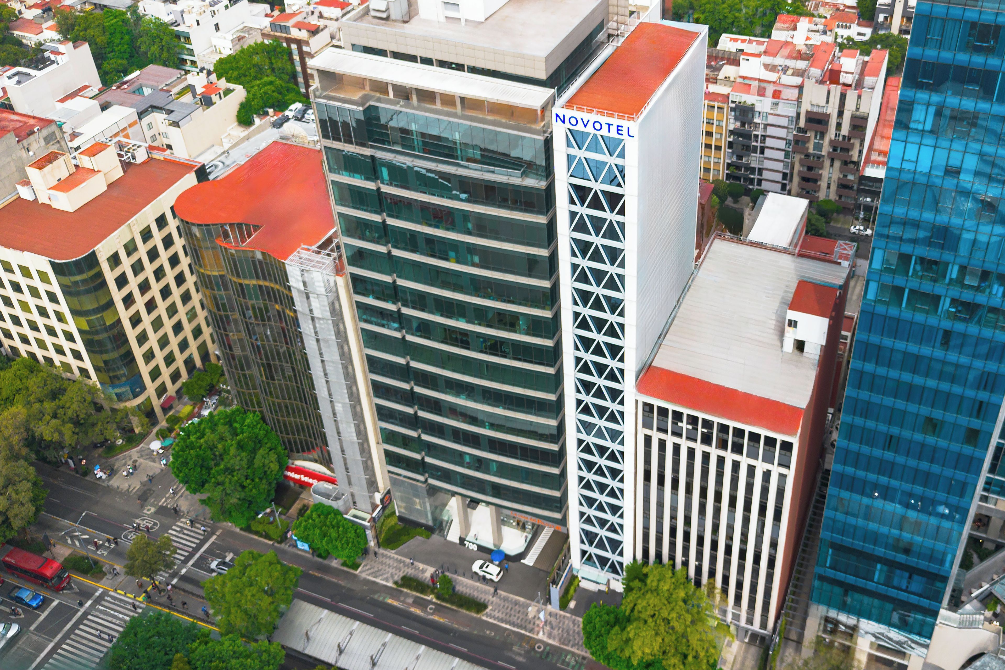 A high-rise building with a prominent 'NOVOTEL' sign, surrounded by other buildings and a street with vehicles and pedestrians.