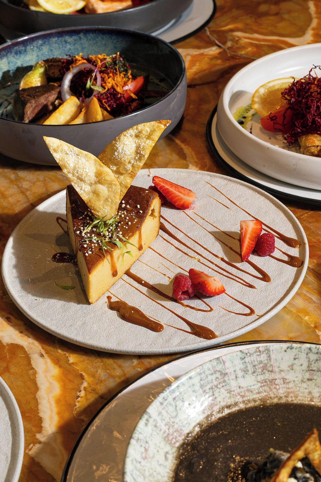 A dessert plate with a chocolate mousse, strawberries, raspberries, and a drizzle of sauce.