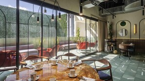 Un comedor moderno con una mesa de mármol, sillas y vistas a zonas verdes a través de amplios ventanales.