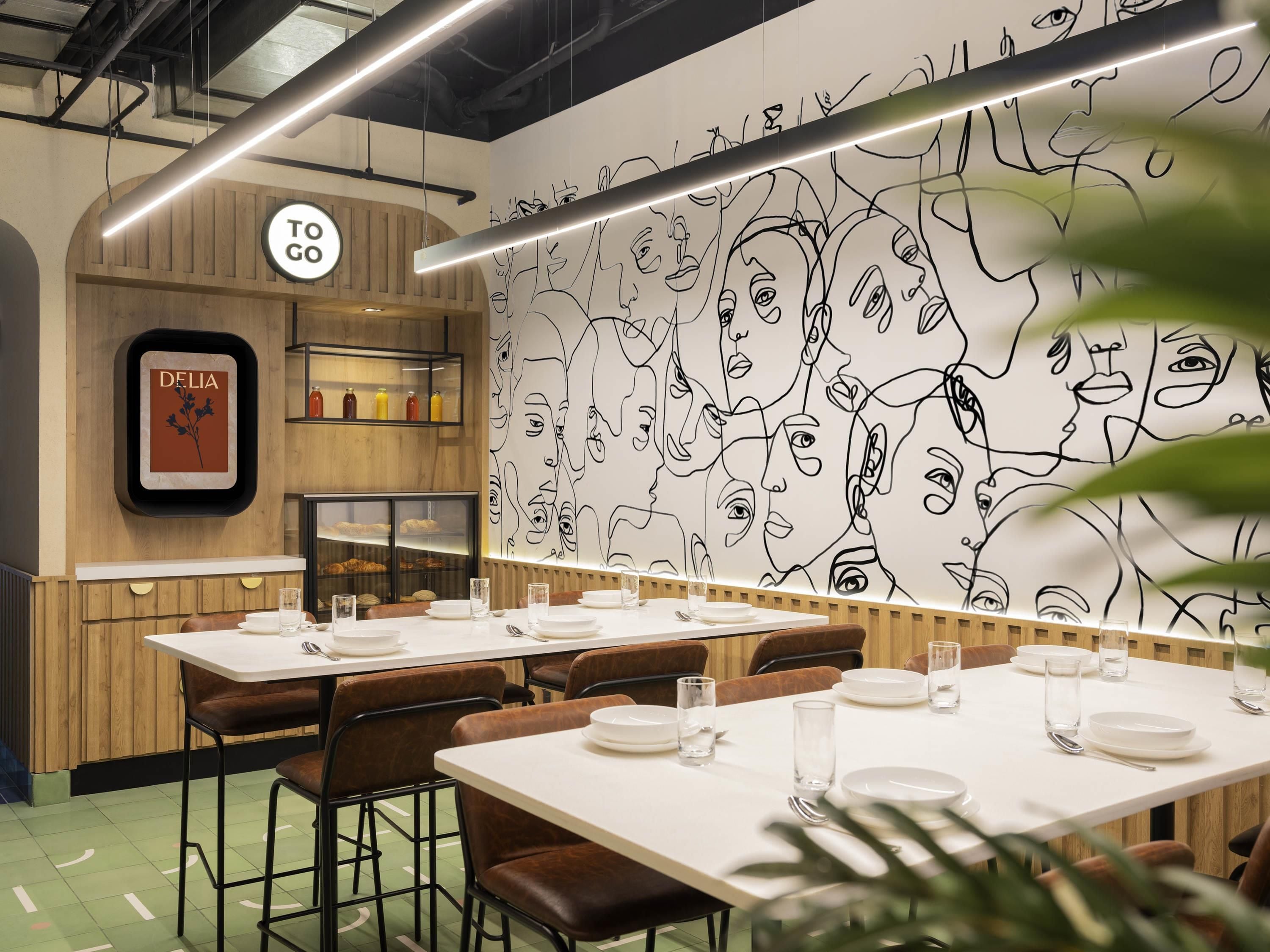 Interior de un restaurante con paredes de paneles de madera, un mural y mesas dispuestas para comer.