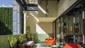 A modern outdoor seating area with orange chairs and potted plants. - Novotel Mexico City World Trade Center (Mexico City)