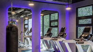 Un gimnasio con cintas de correr, bicicletas estáticas y un saco de boxeo.