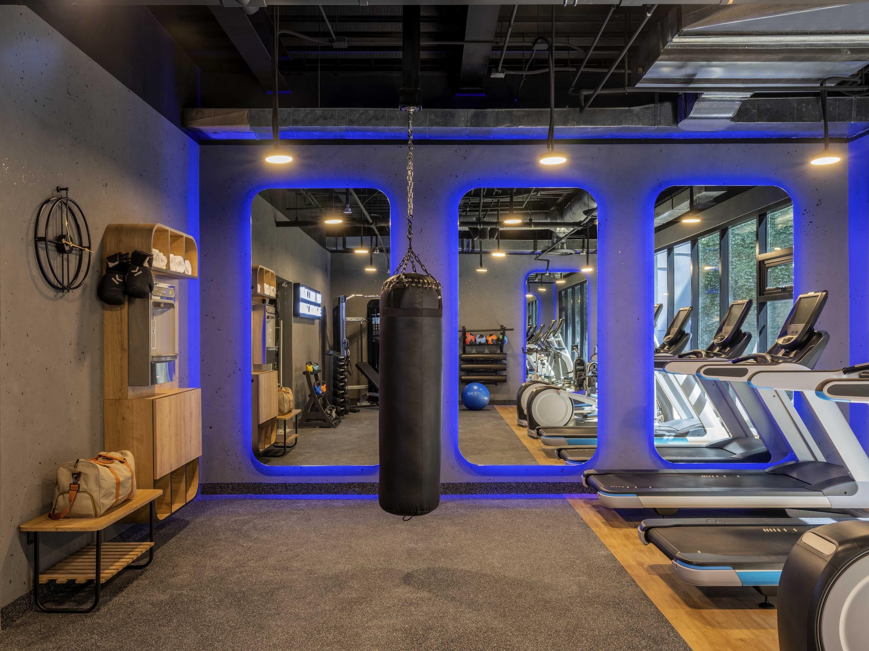 Une salle de sport équipée de matériel d’exercice, d’un sac de frappe et d’un miroir.