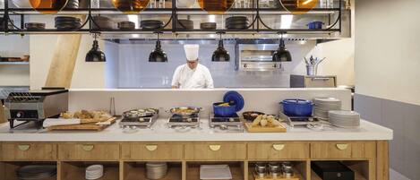 A modern kitchen with a chef at work, equipped with various cooking appliances and neatly organized utensils.