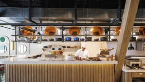 Una cocina moderna con un chef preparando comida, una encimera de madera y varios utensilios y electrodomésticos de cocina.