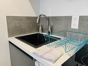 A modern kitchen with a black sink, a stainless steel faucet, and a blue dish rack.