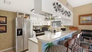 Cozinha moderna com ilha central, eletrodomésticos de aço inoxidável e detalhes decorativos.