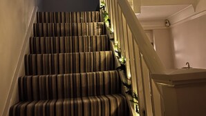 A staircase with striped carpet and white railings, decorated with lights and greenery. - Spacious, Stylish House - 500 yards to the sea front (West Cross)