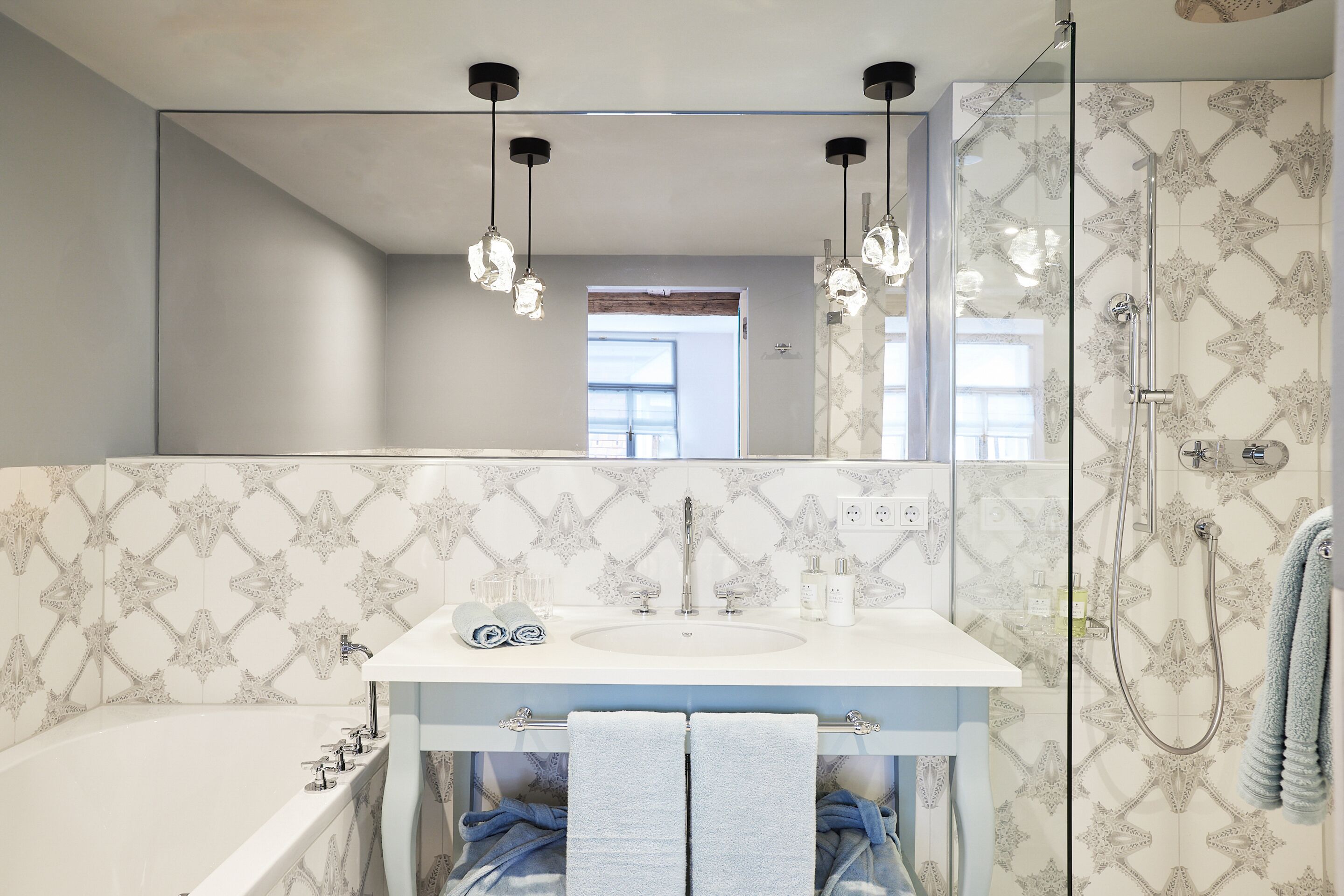 Een badkamer met een grote spiegel, een wastafel, een bad en een douche.