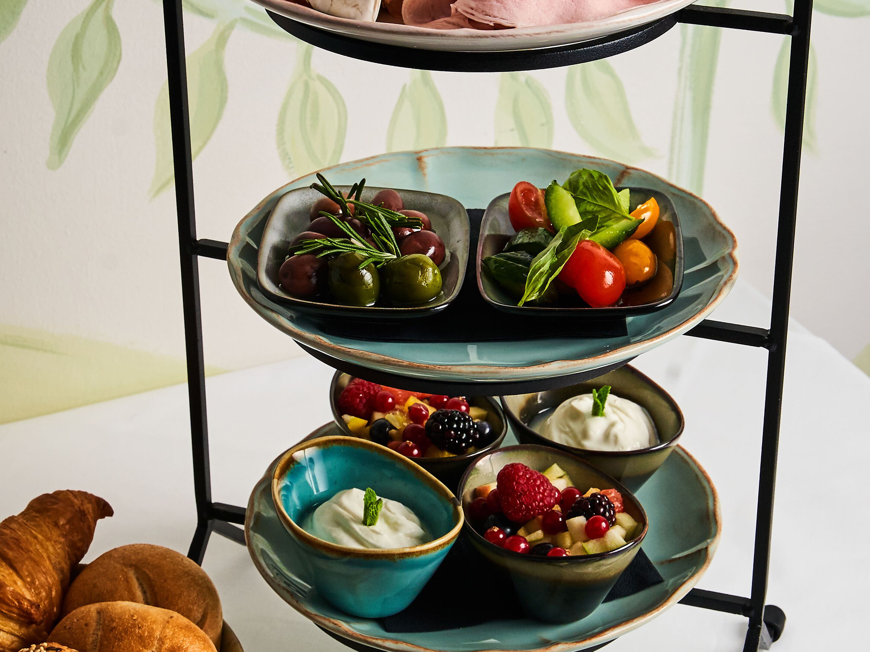 A three-tiered serving tray with various fruits and a bowl of yogurt parfait.