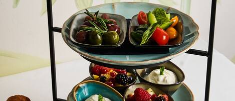 A three-tiered serving tray with various fruits and a bowl of yogurt parfait.