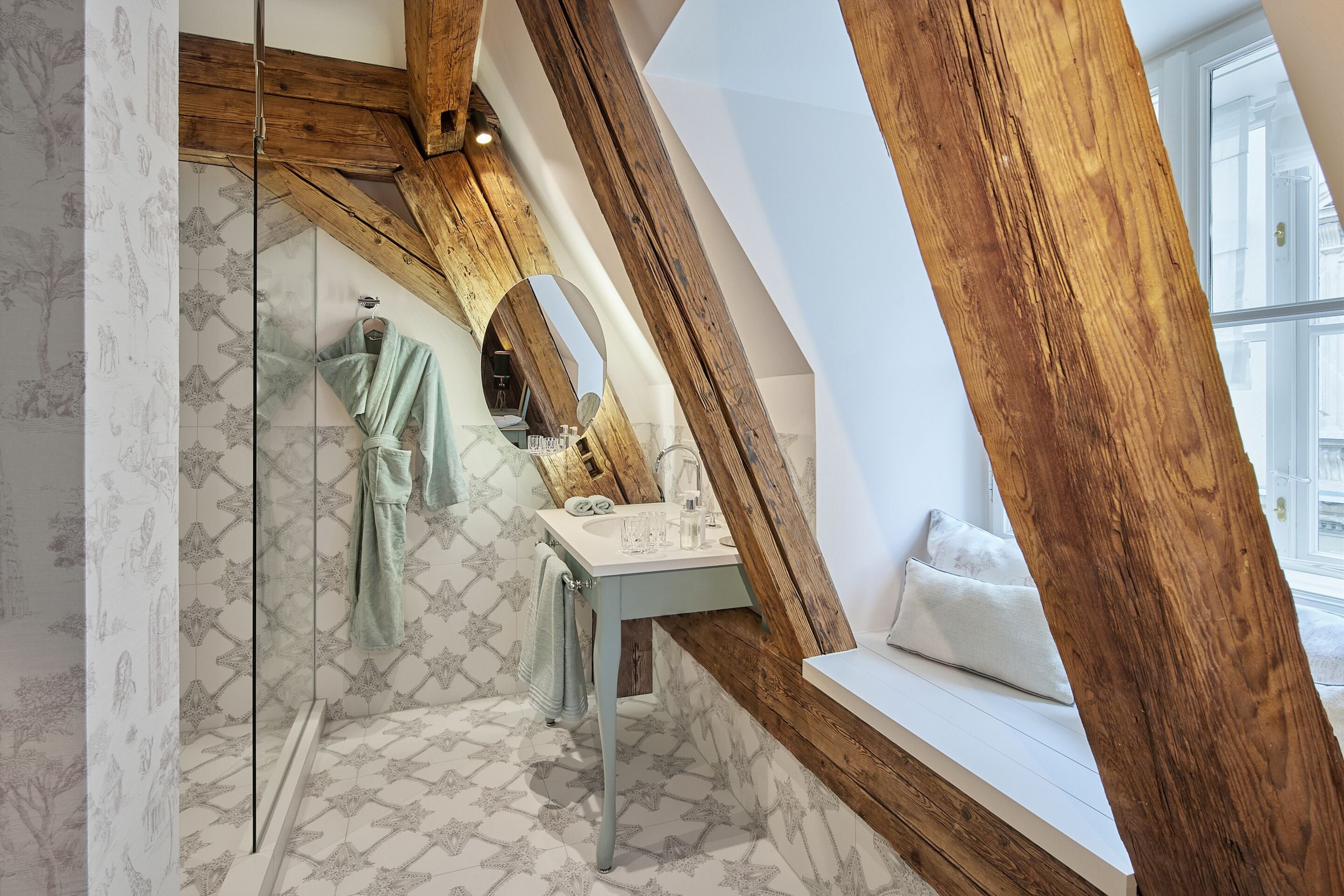 Een badkamer met een vloer met sterveerpatroon, een houten plafond, een wastafel en een vensterbank.