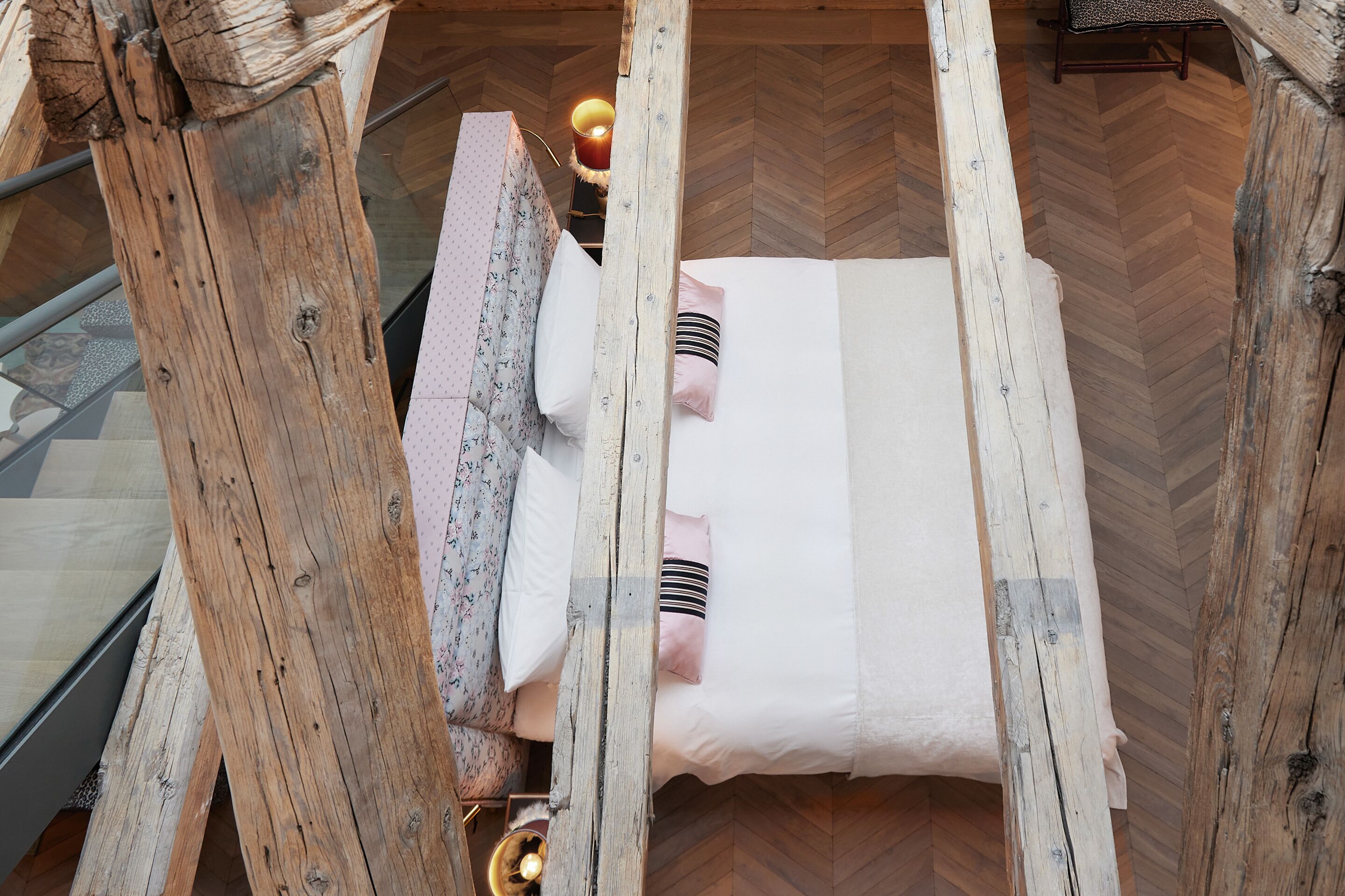 A room with a wooden bed frame, a white mattress, and a patterned headboard.
