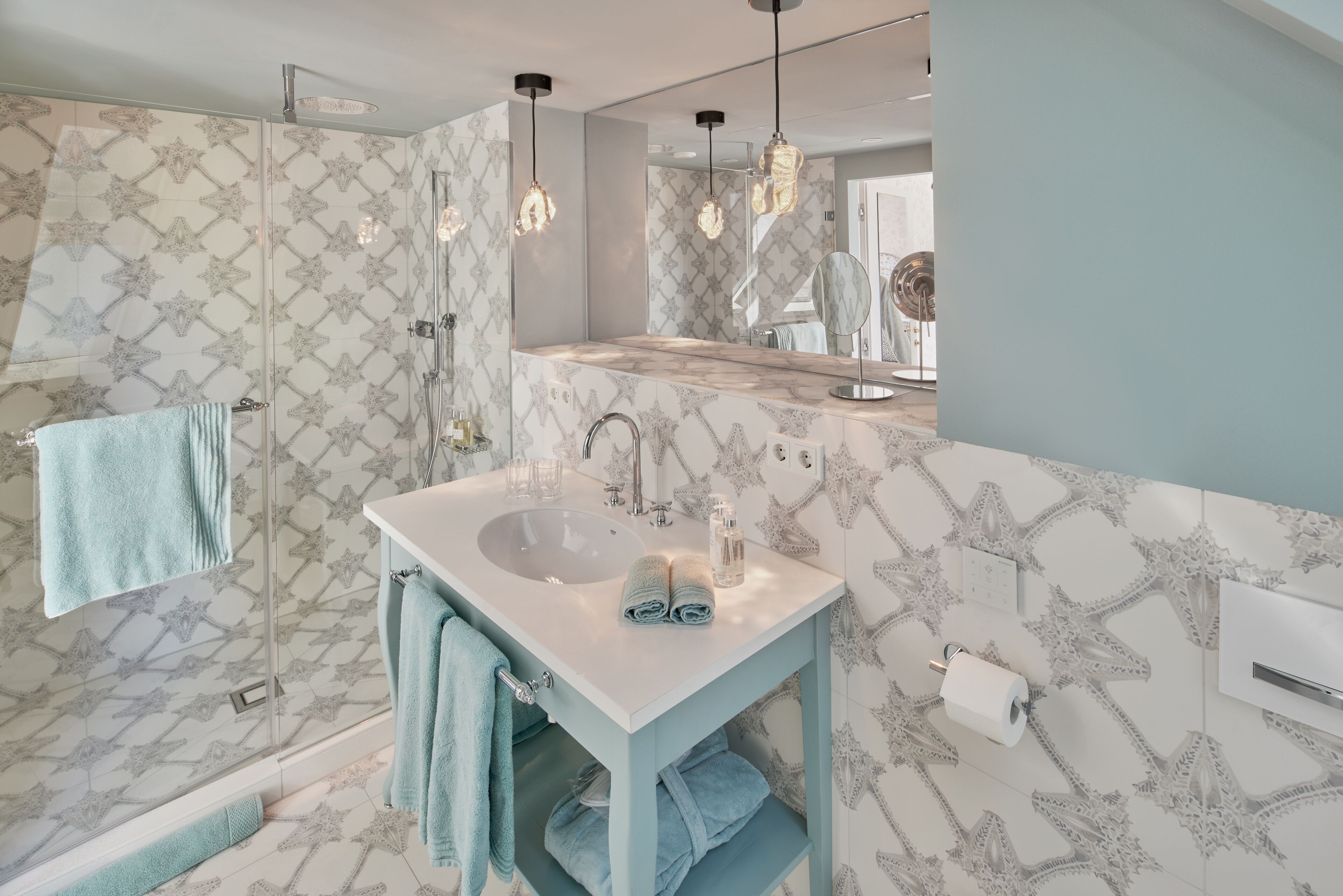 Een moderne badkamer met een witte wastafel, twee handdoekrekken en een douchecabine van glas.