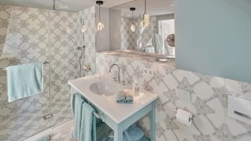 Een moderne badkamer met een witte wastafel, twee handdoekrekken en een douchecabine van glas.