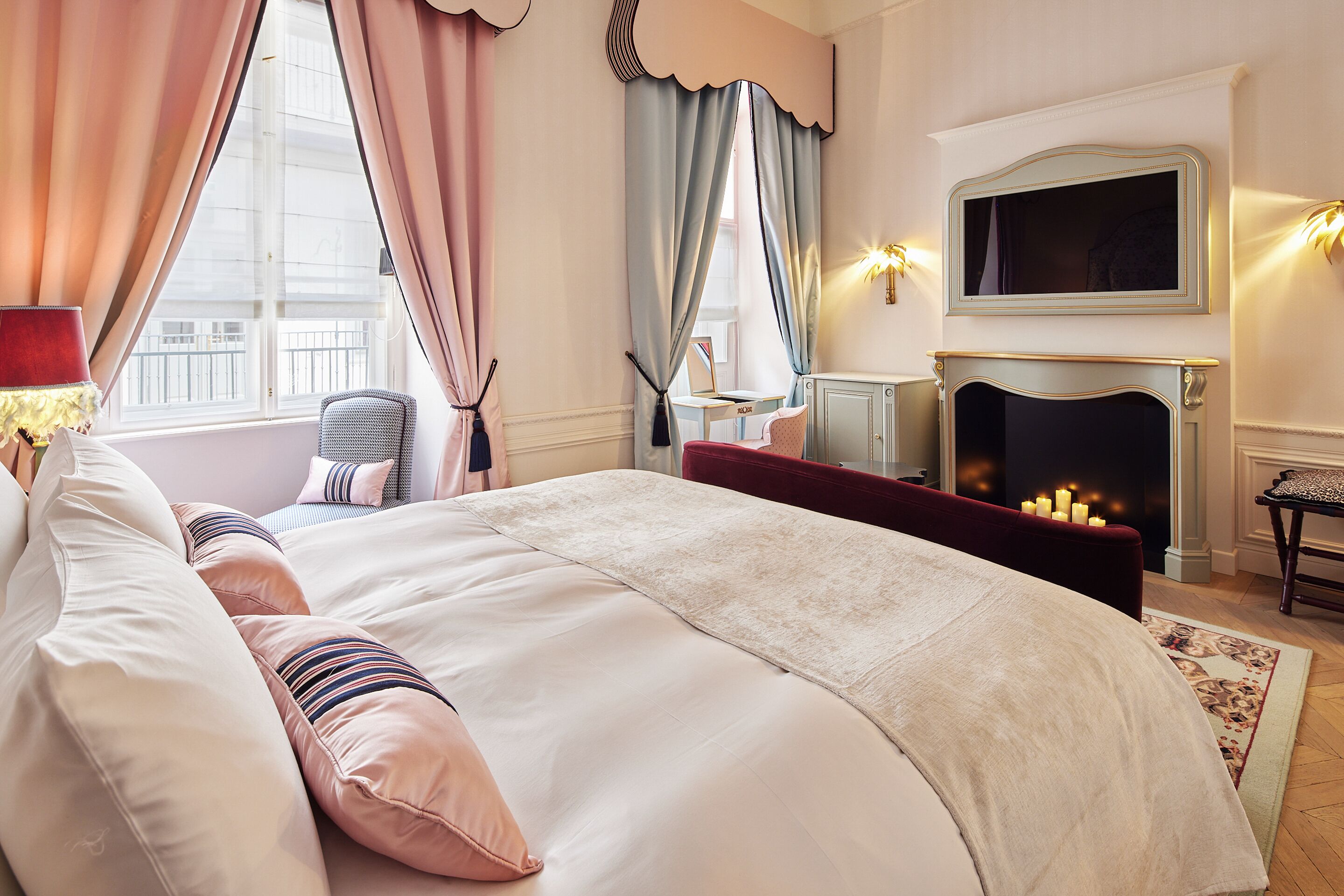 A bedroom with a large bed, a fireplace, and a television on the wall.