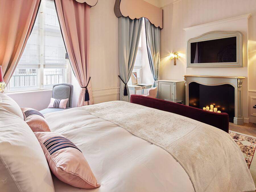 A bedroom with a large bed, a fireplace, and a television on the wall.