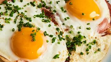 A close-up of two fried eggs with green onions on top.