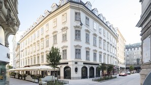 A historic building with classical architecture, featuring multiple windows and a central courtyard with outdoor seating. - The Leo Grand (Vienna)