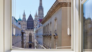 A view of a grand building with multiple spires and a central entrance, viewed through a window with a white frame. - The Leo Grand (Vienna)