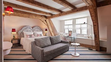 Un dormitorio con cama, sofá, mesita de noche, lámpara, ventana y vistas al exterior.