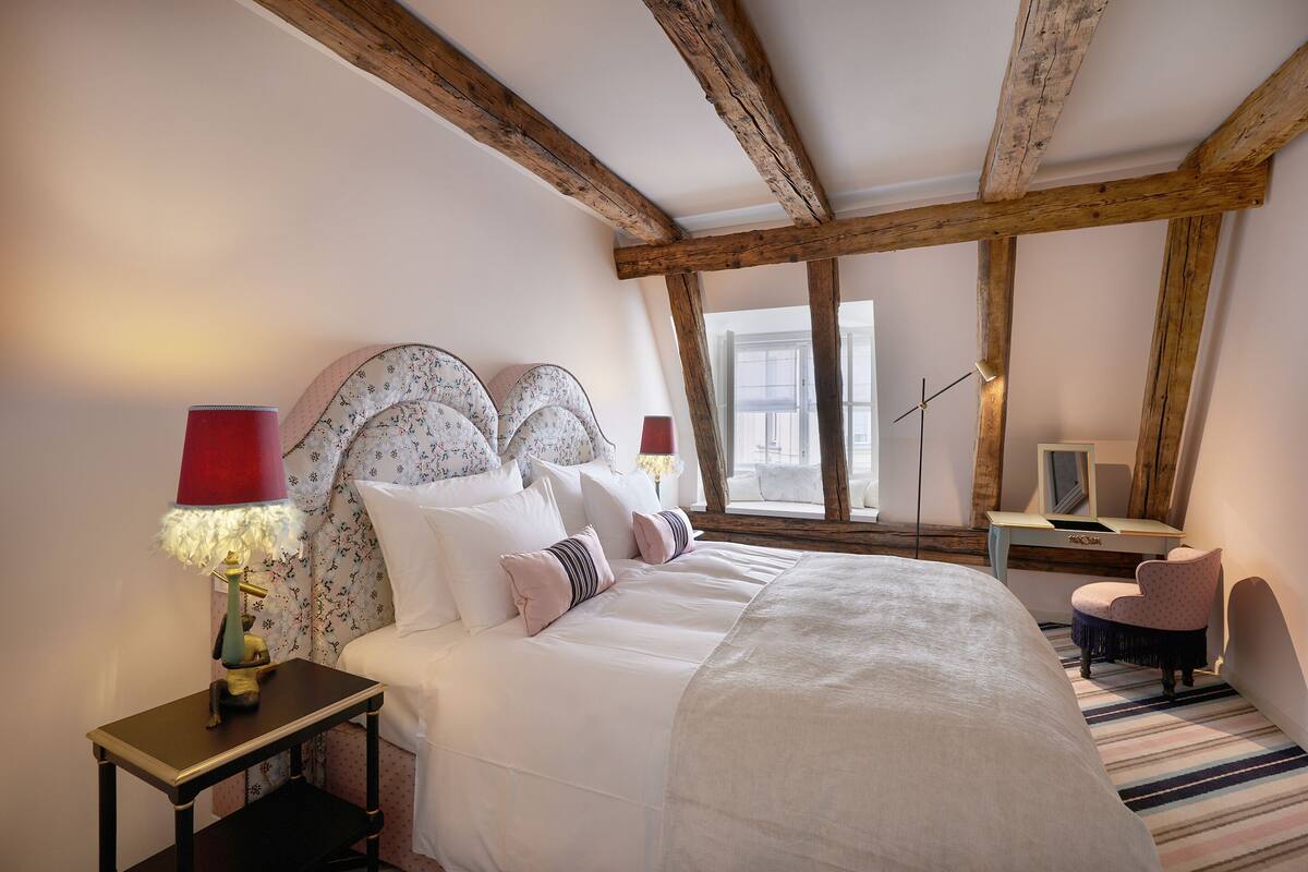 Un dormitorio con una cama grande, un escritorio, una silla y una lámpara.