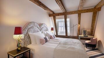 A bedroom with a large bed, a desk, a chair, and a lamp.