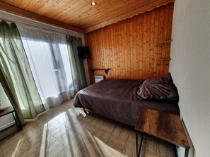 Cozy retreat with a neatly made bed, television, and radiator for a comfortable stay.