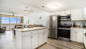 A modern kitchen with white cabinets, stainless steel appliances, and a large island.